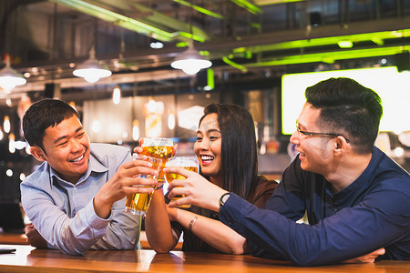 一群快乐的亚洲朋友或办公室同事在酒吧餐厅或俱乐部一起庆祝土司啤酒品脱。Tgif 聚会, 啤酒节, 团队成功事件, 或友谊生活方式概念