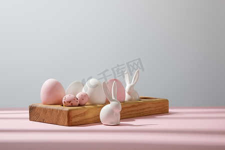 木制木板上的复活节彩蛋，用粉色和灰色装饰兔子