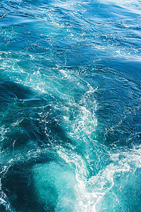 水底慢慢升起的气泡摄影照片_海浪或海浪表面纹理.带浪花的夏季蓝色水底.