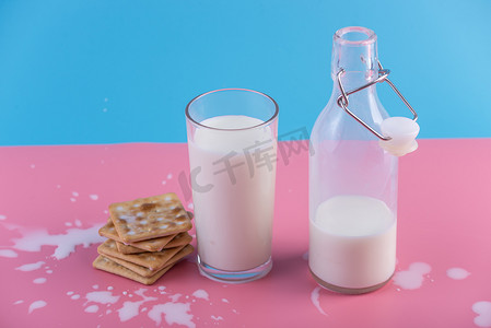 简约饼干摄影照片_玻璃瓶新鲜牛奶和饼干在柔和的背景。多彩简约。健康乳制品与钙的概念