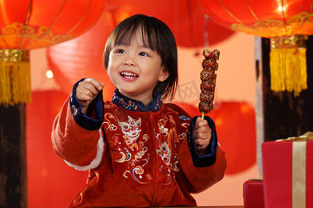 中国传统成长摄影照片_可爱的小男孩拿着糖葫芦庆新年