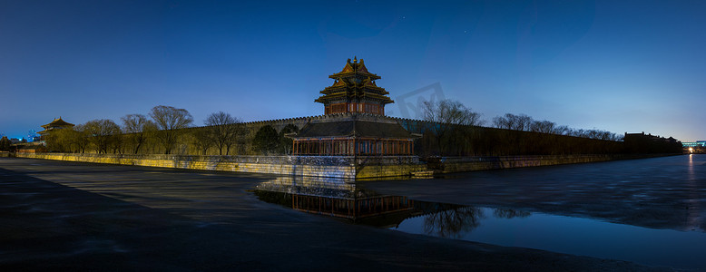 城墙故宫摄影照片_位于中国北京的紫禁城故宫博物馆的西北塔和城墙的全景夜景，反映在半冰冻的护城河上