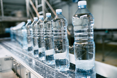 蓝色瓶子摄影照片_瓶装水厂.处理纯泉水并将其装瓶成蓝色瓶子的瓶装水生产线有选择的重点. 
