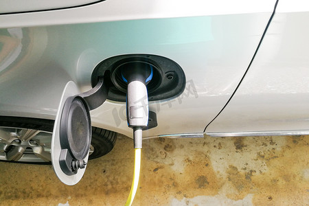 电动混合动力汽车的特写镜头被充电在墙上的插座