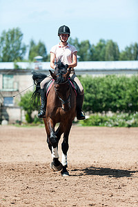 女子骑马摄影照片_少年女子骑马骑马在竞技场上运动训练。动感多彩的户外垂直图像.