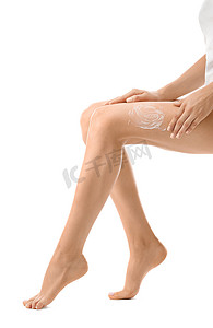 年轻妇女在她的腿涂上奶油后脱毛白色背景