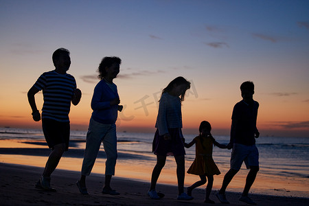 奔跑的人剪影摄影照片_在海边度假的快乐家庭