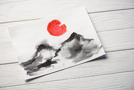 山水画背景摄影照片_日本山水画和木制背景下的红色太阳的纸的顶部视图