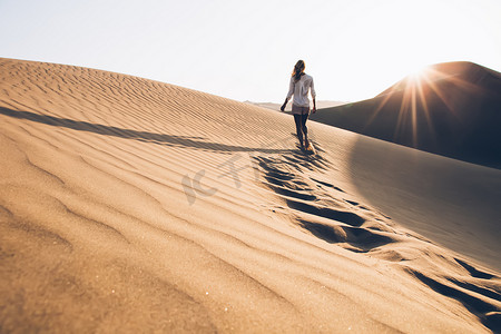 叹为观止摄影照片_夏夜，女性游人在自然环境中探索野生撒哈拉沙漠的背景图，女游客在沙滩上漫步，发现令人叹为观止的萨法里