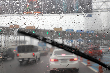 狗尾巴草前景摄影照片_高速公路收费站雨天使用汽车挡风玻璃雨刷开车的前景.