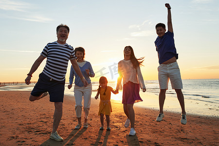 海滩晚霞摄影照片_在海边度假的快乐家庭
