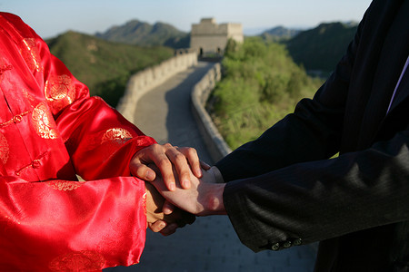 中国传统人士与外国商务人士在长城上握手特写