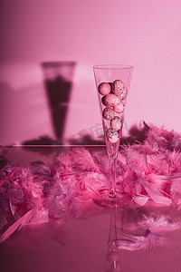 鹌鹑蛋在香槟酒长笛与羽毛在光滑的背景。用粉红色的色彩创作静谧的生活.