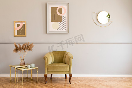 时尚和豪华的客厅的公寓内部与优雅的绿色扶手椅，复古的桌子与鲜花和别致的配件。在成型灰墙上模拟绘画框架。最小的家居装饰.