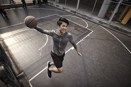年轻的亚洲男子篮球运动员试图在室外场地灌篮