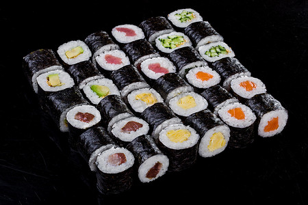 tuna摄影照片_Sushi tuna, omelette, avocado, salmon, cucumber on a black background