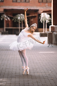 美丽的年轻芭蕾舞演员在芭蕾舞裙在城市街道上跳舞      