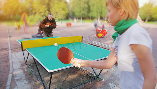 乒乓球女孩摄影照片_一群快乐的年轻朋友, 女孩和男孩, 在户外打乒乓球和球。健康运动的概念和真正的情感。积极的生活方式, 有趣的休息。两个人或玩家游戏.