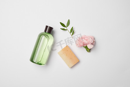 在白色背景的不同的化妆品瓶、肥皂、茶树分支和康乃馨花的顶视图