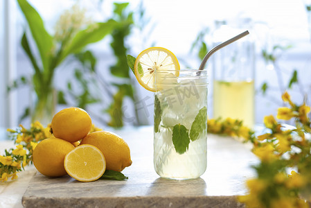 柑橘冰柠檬水在水壶和眼镜柠檬片和薄荷叶装饰和大理石桌子上的天然背景。新鲜的夏天喝美丽的图画。复制空间