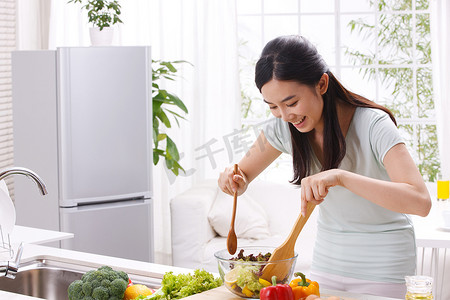 双开门冰箱摄影照片_年轻女人在厨房做饭