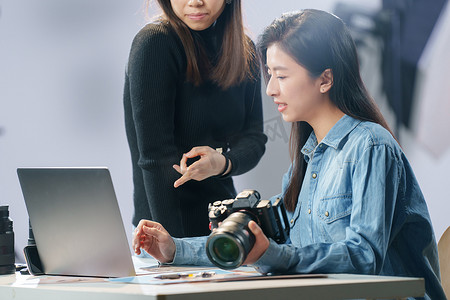 商务场景图片摄影照片_在工作室里讨论工作的青年女摄影师