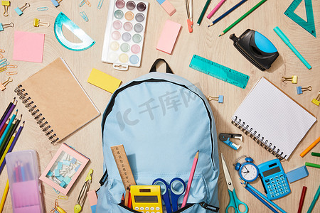 木桌上的蓝色背包，各种学习用品的顶视图