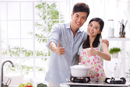 大拇指图片摄影照片_年轻夫妇在厨房做饭