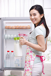 年轻女人站在冰箱前