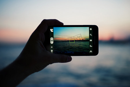 智能手机拍摄日落的手