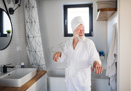 例行公事摄影照片_老人在家里的室内浴室里做早晨的例行公事.