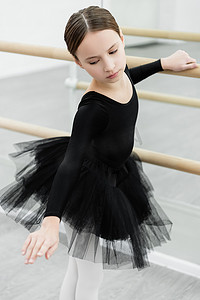 身穿黑色芭蕾服装的少女在工作室的Barre锻炼