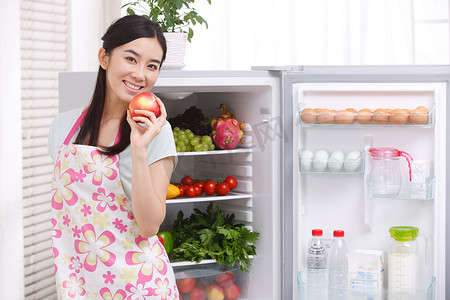 冰箱电器摄影照片_一个年轻女人在厨房做饭