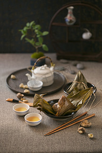 中式食品糯米金字塔形竹叶包饺子与中式茶具摆在桌面上.