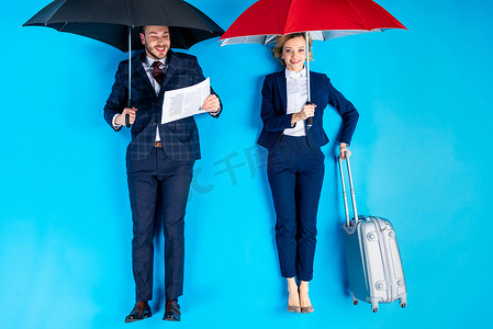异人之下摄影照片_妇女与手提箱和人与报纸站立在雨伞之下在蓝色背景