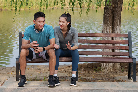 健身的青年情侣坐在长椅上聊天