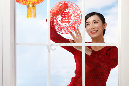 春节背景窗户摄影照片_青年女人新年贴窗花
