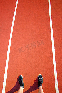 男子的脚穿着黑色运动鞋停留在红色跑道在体育场。概念运行。爱运动