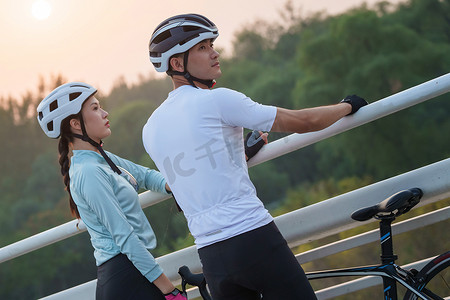 骑行的青年情侣站在桥上看风景