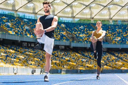 年轻的运动夫妇热身腿前慢跑跑道上体育场馆