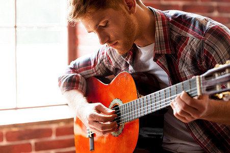 坐弹吉他摄影照片_英俊的男人弹吉他.
