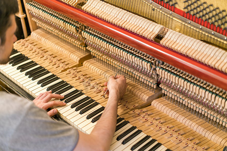 钢琴调音过程。手和调谐器工具在大钢琴上的特写。调音期间Upright钢琴的详细视图.