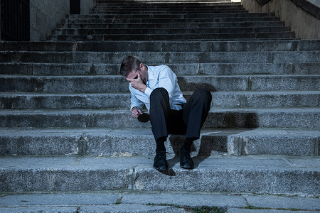 年轻的商人摄影照片_年轻的商人哭着放弃失落在忧郁中坐在街头的楼梯上痛苦的情绪痛苦, 悲伤的精神健康概念照片