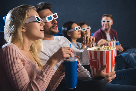 多民族朋友在3d 眼镜与爆米花一起看电影在电影院