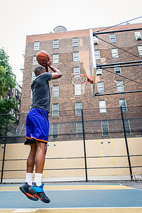 training摄影照片_Afro-american basketball player training on a court in New York - Sportive man playing basket outdoors