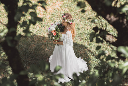 美丽温柔年轻新娘在公园捧花的高角度观  