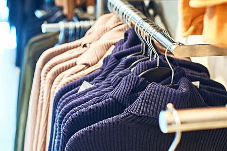 女装潮流摄影照片_零售服装店的衣架上有不同颜色的女式套头毛衣.