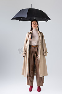 秋装新品上新摄影照片_全景迷人的女人穿着时髦的秋装，头戴灰色的黑色雨伞
