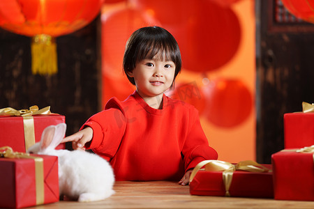 喜庆小动物摄影照片_可爱的小男孩收到新年礼物小兔子