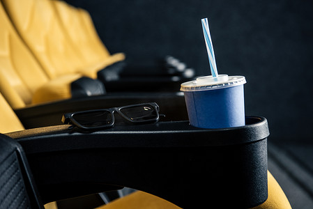 带处置杯和3d 眼镜的空橙色电影院座椅的选择性焦点